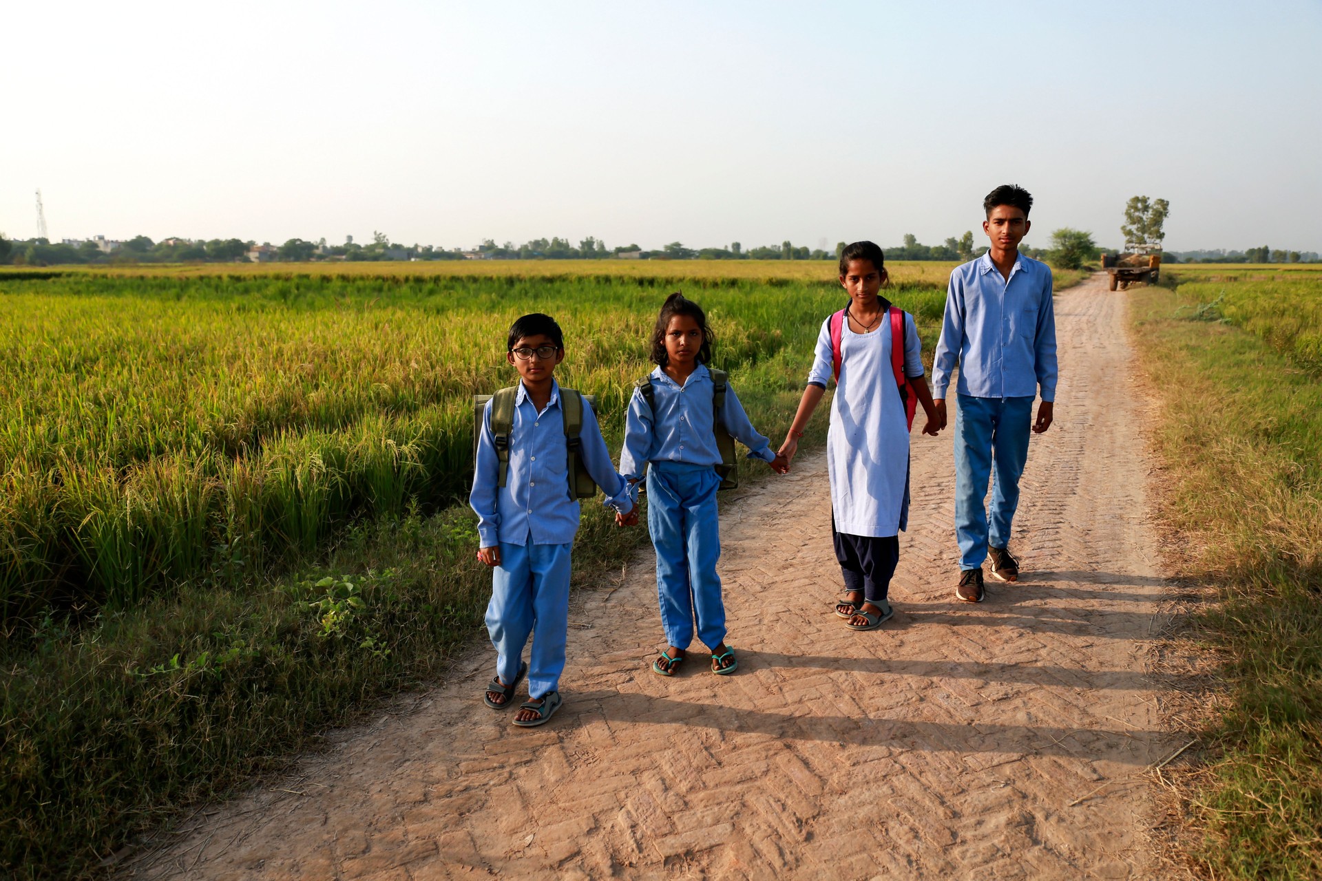 Elementary age school students walking on country road after school vacation
