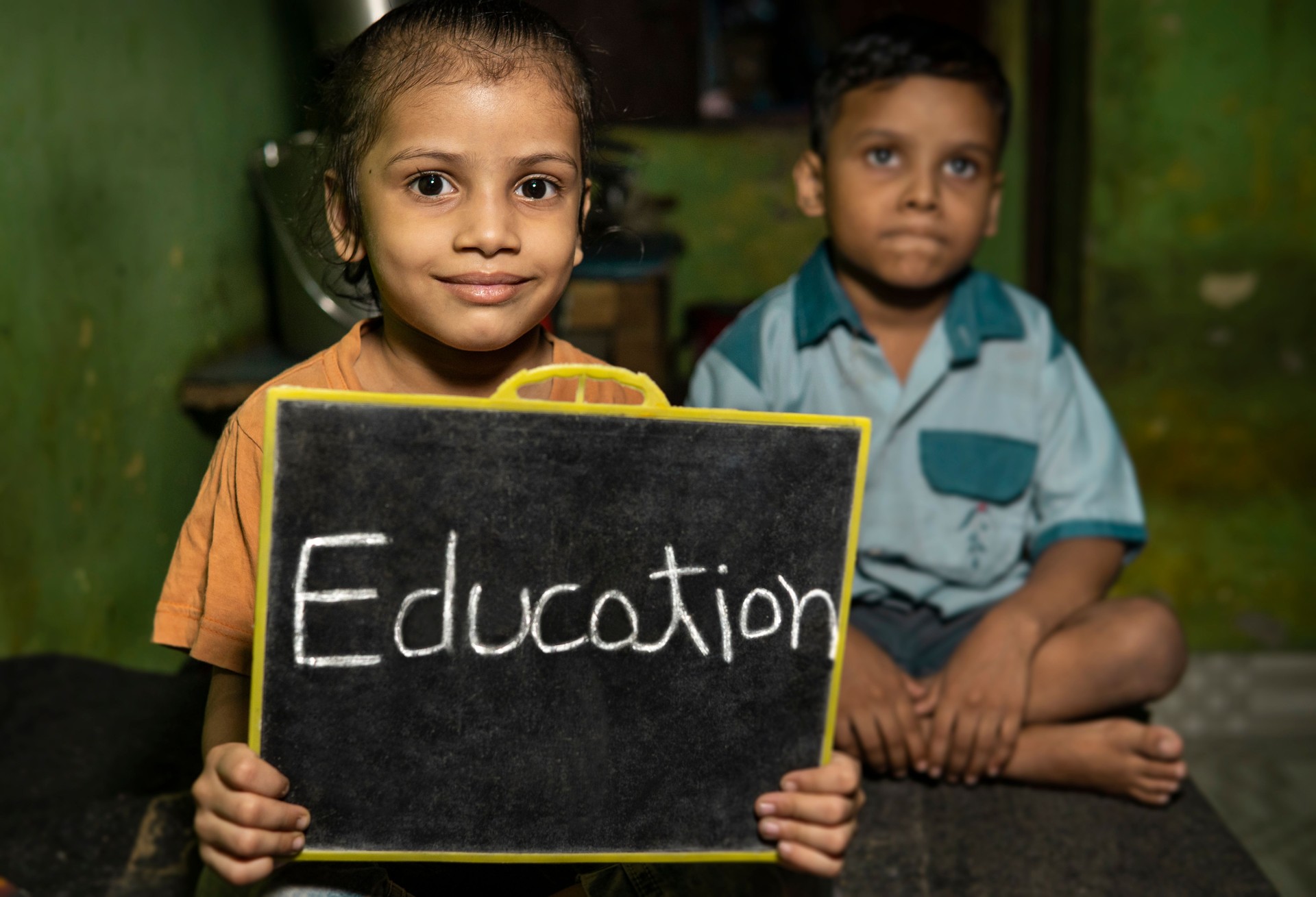Portrait of rural children holding slate board with word education and smiling.